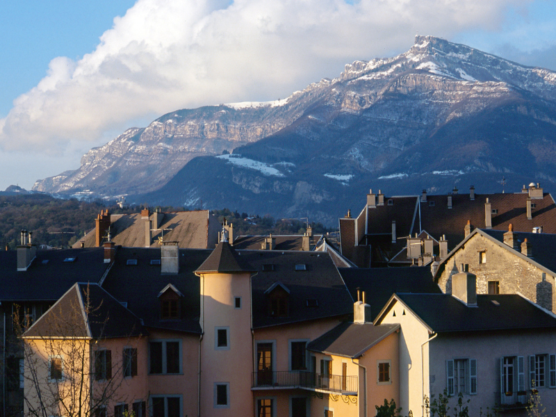 Consultant SEO Chambéry - Vue des toits de Chambéry avec les montagnes en arrière-plan sous un ciel partiellement nuageux.