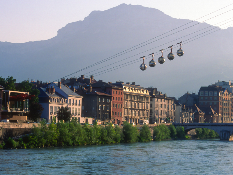 Consultant SEO Grenoble - Téléphérique de Grenoble surplombant la rivière Isère avec les montagnes en arrière-plan.